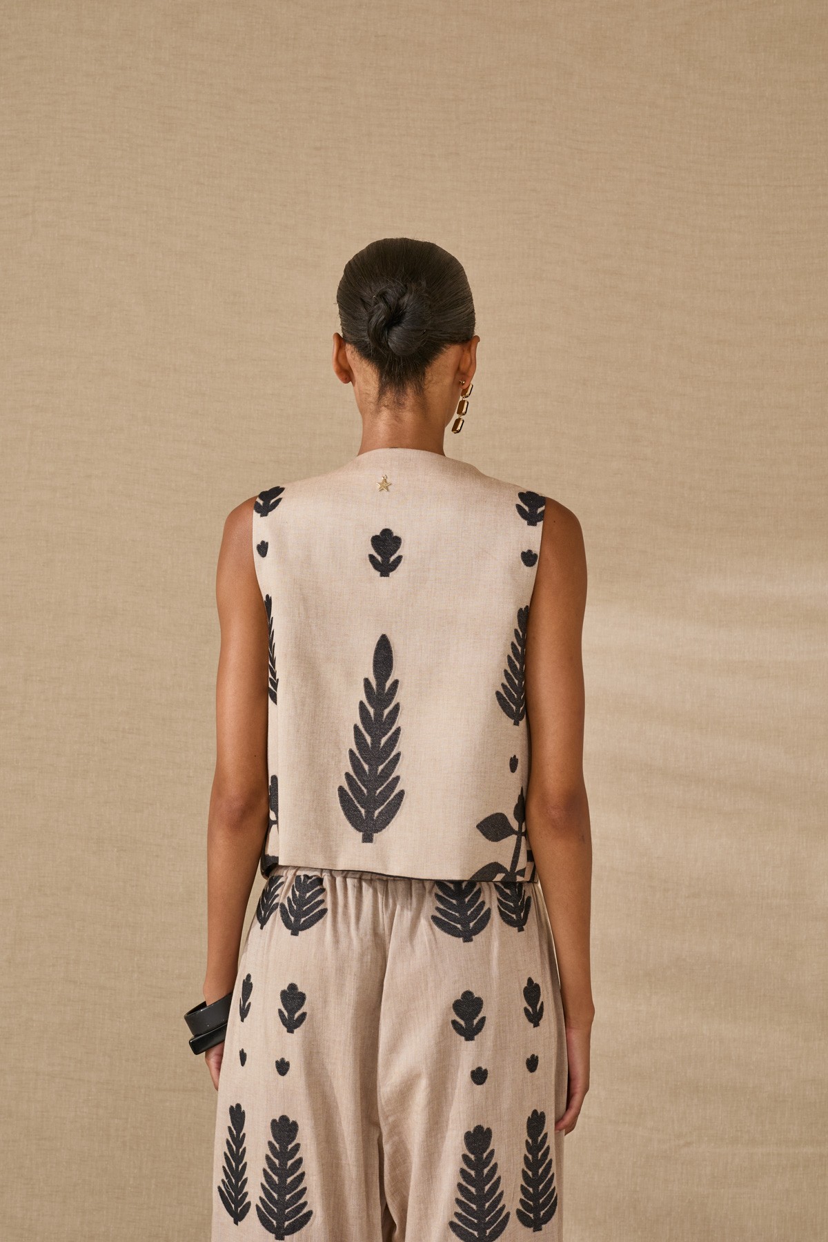 Αμάνικο γιλέκο-top με ανάγλυφα μαύρα μοτίβο. Για ενημερωμένο look συνδύασε το με το παντελόνι του