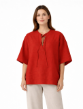 Relaxed blouse with wide sleeves, a round neckline, and a subtle front opening with tie strings.